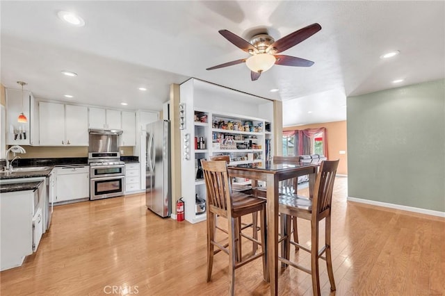 dining area with ceiling fan, sink, and light hardwood / wood-style flooring