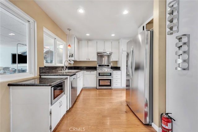 kitchen with stainless steel appliances, white cabinetry, hanging light fixtures, and sink