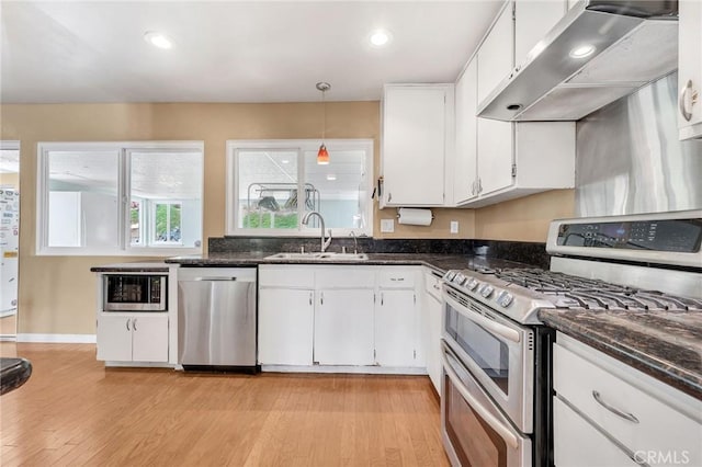 kitchen featuring wall chimney exhaust hood, stainless steel appliances, sink, white cabinets, and light hardwood / wood-style floors