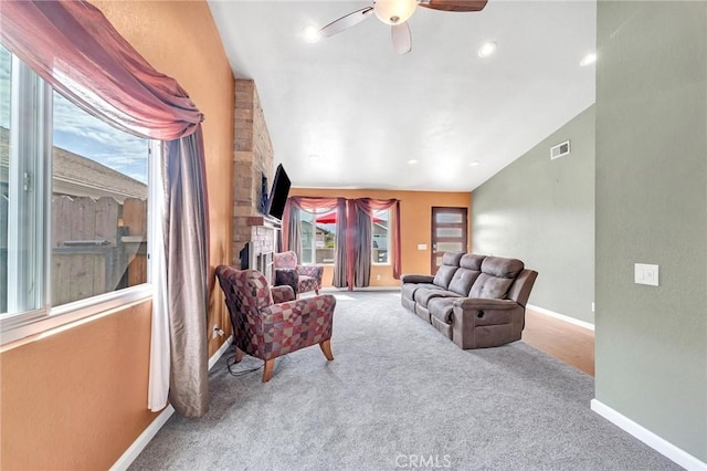 carpeted living room featuring ceiling fan, a fireplace, and vaulted ceiling