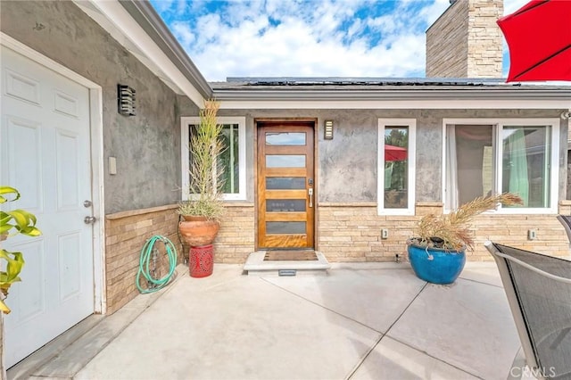 view of exterior entry with a patio area