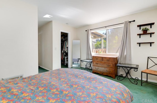 carpeted bedroom with a walk in closet and a closet