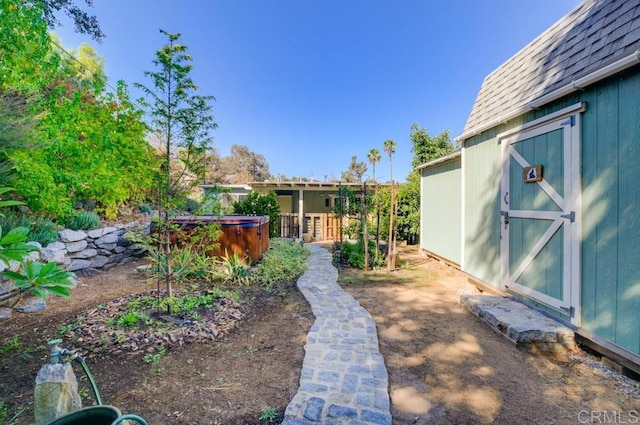 view of yard featuring a storage shed and a hot tub