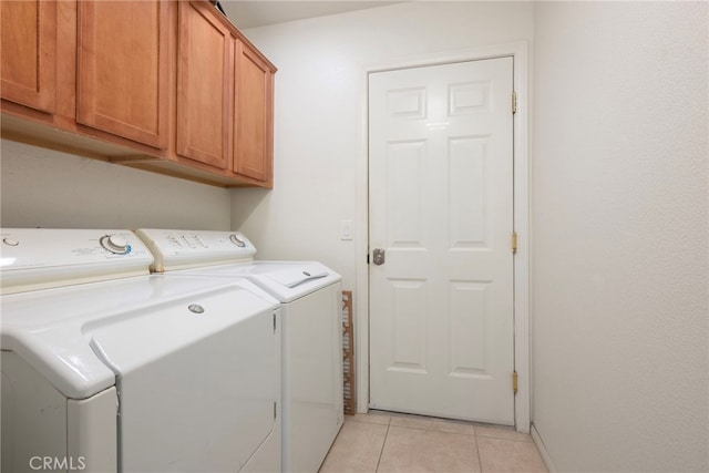 laundry room with washer and clothes dryer, light tile patterned floors, and cabinets