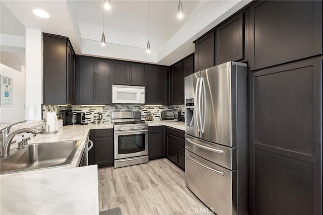 kitchen featuring stainless steel appliances, backsplash, sink, and light wood-type flooring