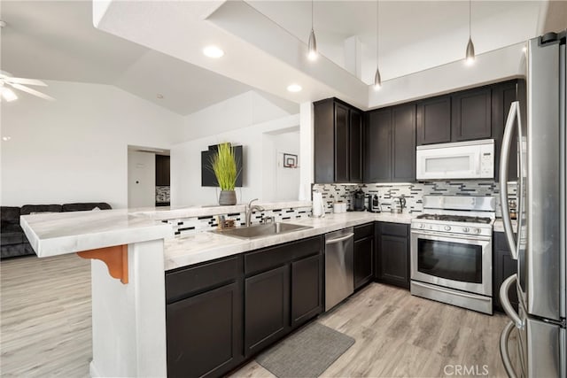 kitchen with pendant lighting, sink, decorative backsplash, kitchen peninsula, and appliances with stainless steel finishes