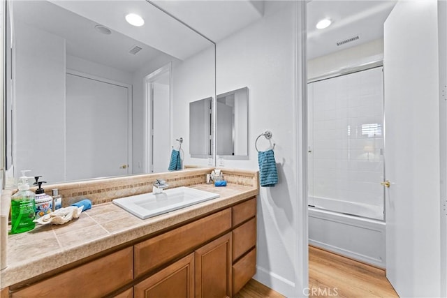 bathroom featuring vanity, combined bath / shower with glass door, and wood-type flooring