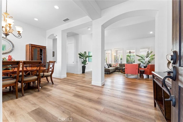 dining room with beamed ceiling, a notable chandelier, and light hardwood / wood-style floors