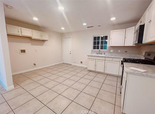 kitchen with light stone counters, gas range gas stove, sink, white cabinetry, and light tile patterned floors