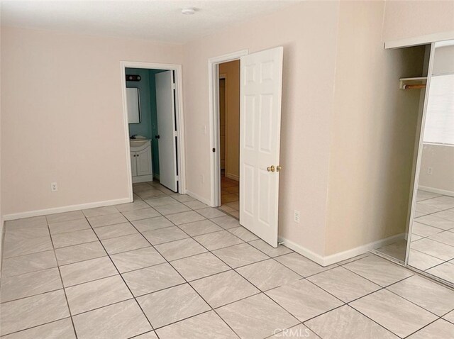 unfurnished bedroom with ensuite bath and light tile patterned floors