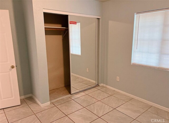 unfurnished bedroom with a closet and light tile patterned floors