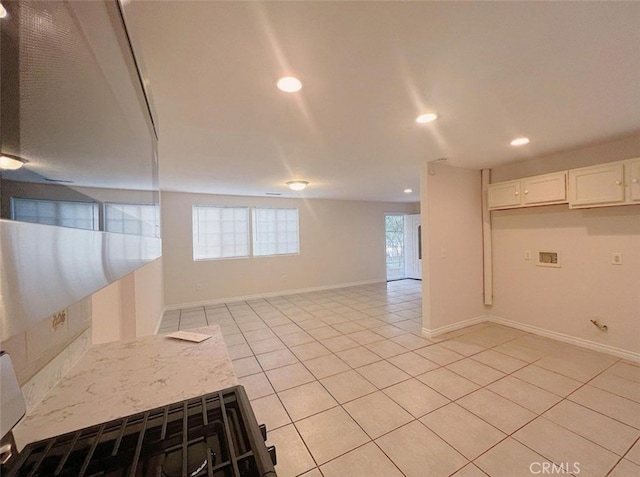 kitchen featuring light stone countertops, light tile patterned floors, and white cabinetry