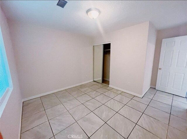 unfurnished bedroom with a closet and light tile patterned floors