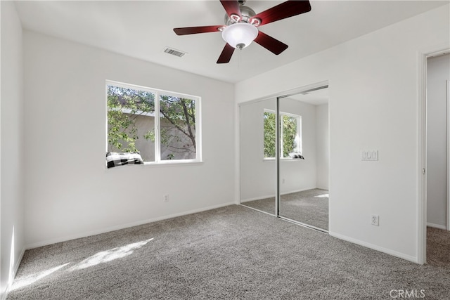 unfurnished bedroom with multiple windows, a closet, carpet flooring, and ceiling fan