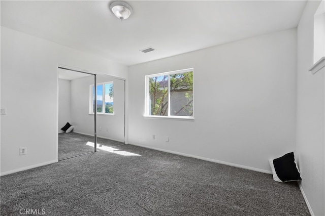 unfurnished bedroom with a closet and dark colored carpet