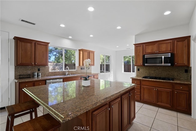 kitchen featuring appliances with stainless steel finishes, a wealth of natural light, sink, and a kitchen island