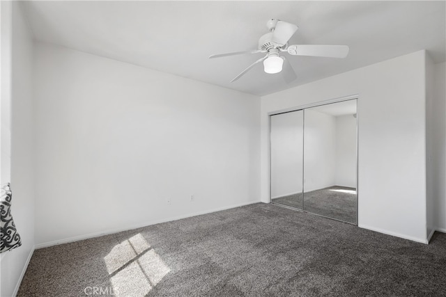 unfurnished bedroom featuring dark carpet, a closet, and ceiling fan