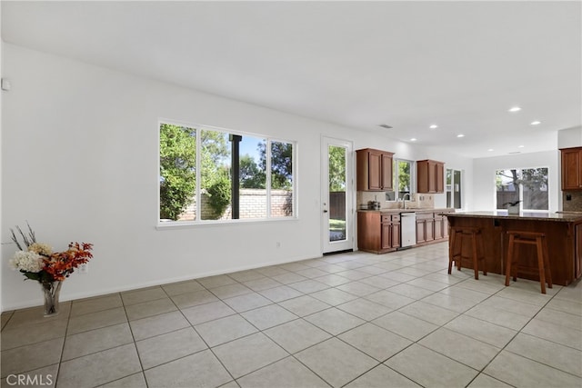 kitchen with stainless steel dishwasher, light tile patterned floors, sink, and a breakfast bar area