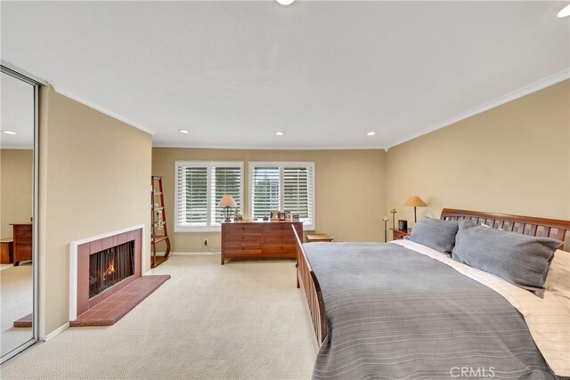 bedroom with a tile fireplace, light colored carpet, and ornamental molding