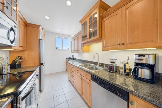 kitchen with light tile patterned flooring, sink, appliances with stainless steel finishes, and dark stone counters