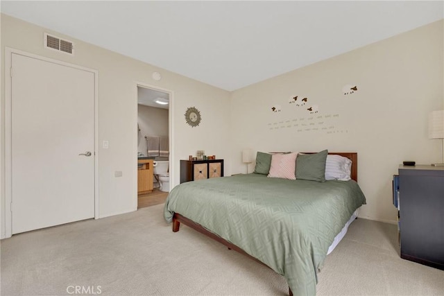 bedroom with connected bathroom and carpet floors