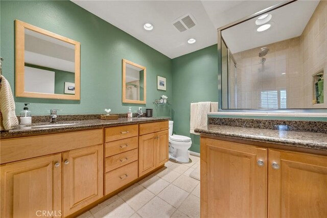 bathroom featuring a tile shower, vanity, toilet, and tile patterned floors