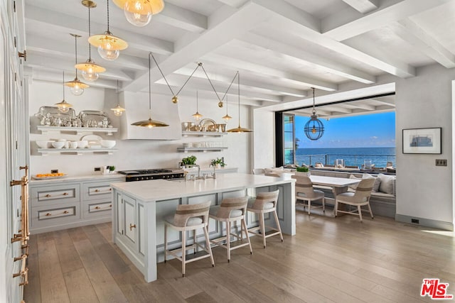 kitchen with hanging light fixtures, a water view, a breakfast bar area, and dark hardwood / wood-style floors