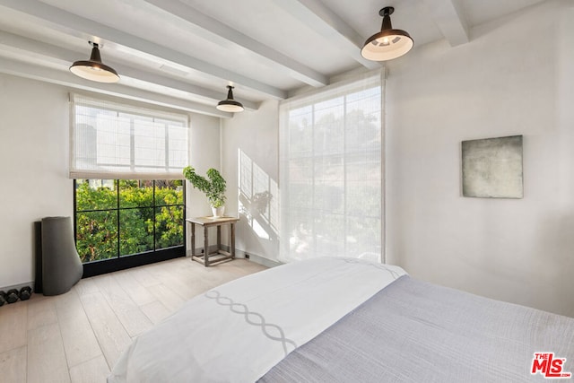 bedroom featuring beam ceiling, light hardwood / wood-style floors, and multiple windows