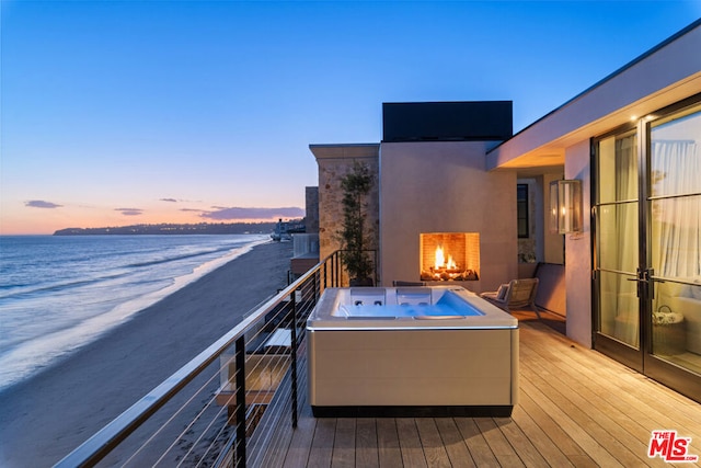 balcony at dusk featuring a water view