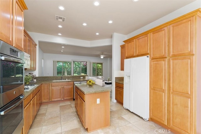 kitchen featuring light tile patterned flooring, white appliances, light stone countertops, a kitchen island, and kitchen peninsula