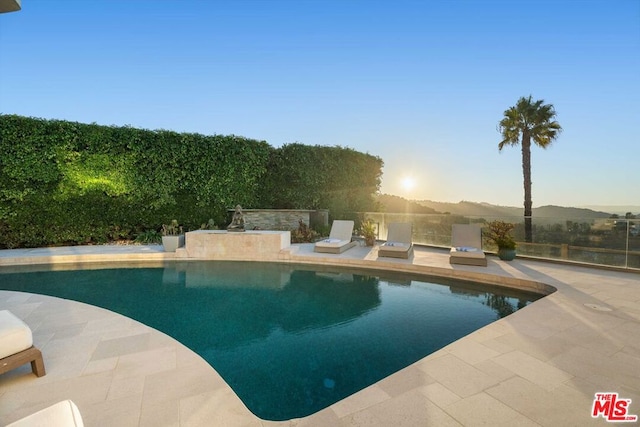 pool at dusk featuring a mountain view and a patio area