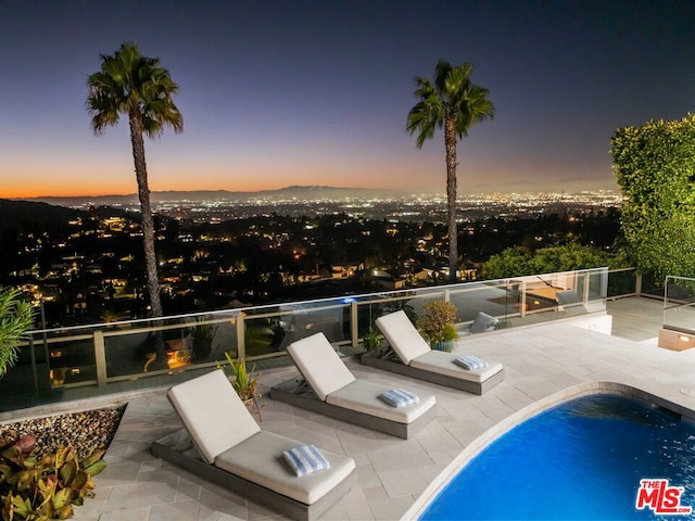 pool at dusk featuring a patio area