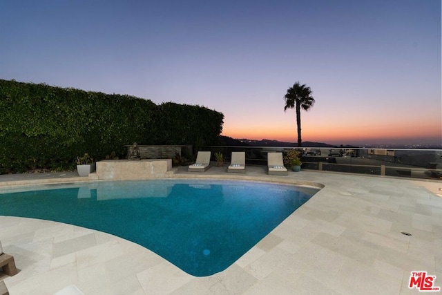 pool at dusk with a patio area