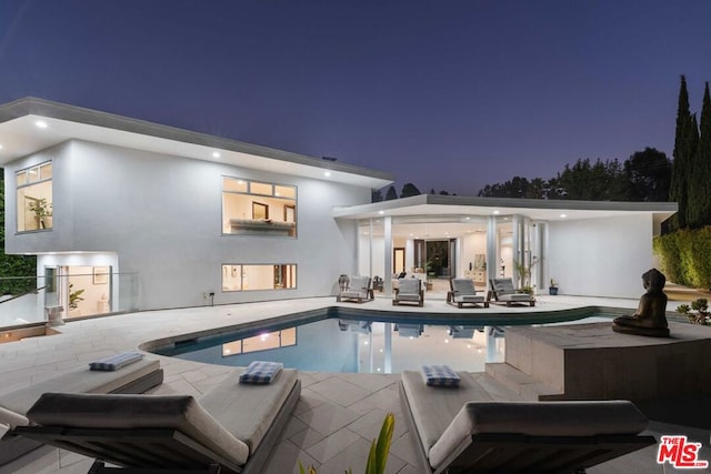 pool at dusk with a patio