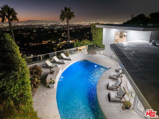 pool at dusk with a patio area