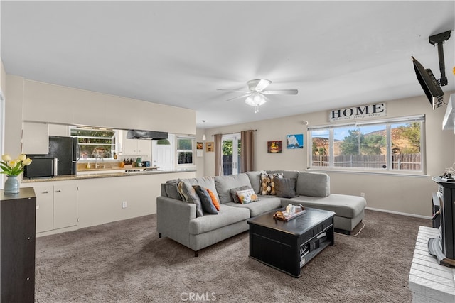 carpeted living room with ceiling fan and sink