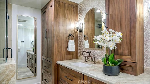 bathroom featuring vanity, an enclosed shower, and backsplash