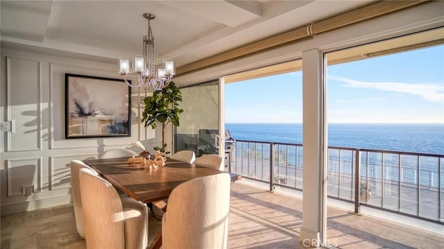 dining room featuring a water view, a beach view, a wealth of natural light, and a chandelier