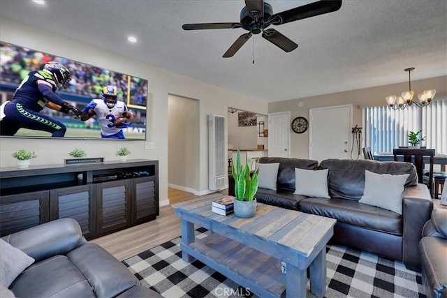 living room with ceiling fan with notable chandelier and light wood-type flooring