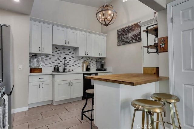 kitchen with wood counters, sink, decorative light fixtures, a kitchen bar, and white cabinetry