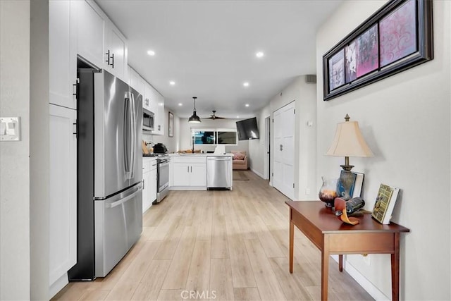 kitchen with pendant lighting, white cabinetry, stainless steel appliances, and light hardwood / wood-style flooring