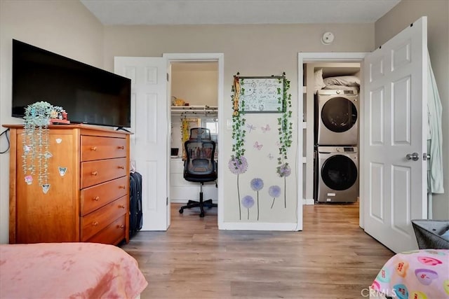 bedroom with stacked washer / dryer, a walk in closet, a closet, and light wood-type flooring