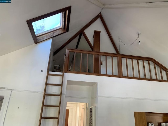 staircase featuring beamed ceiling, a skylight, and high vaulted ceiling