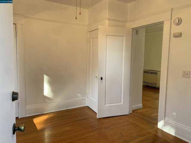 unfurnished bedroom featuring a closet, radiator heating unit, and dark hardwood / wood-style floors