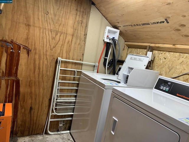 laundry room with wooden walls and washer and dryer