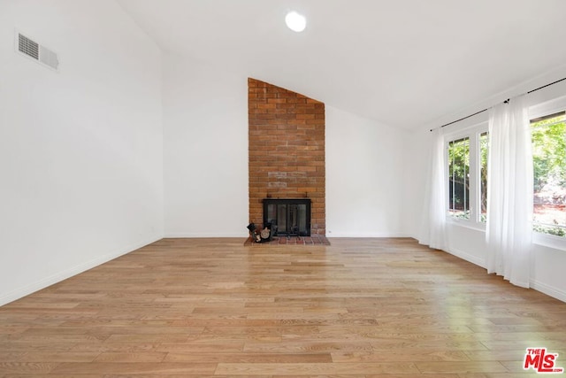 unfurnished living room featuring lofted ceiling, light wood-type flooring, and a fireplace