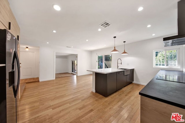 kitchen with pendant lighting, light hardwood / wood-style flooring, sink, extractor fan, and black appliances