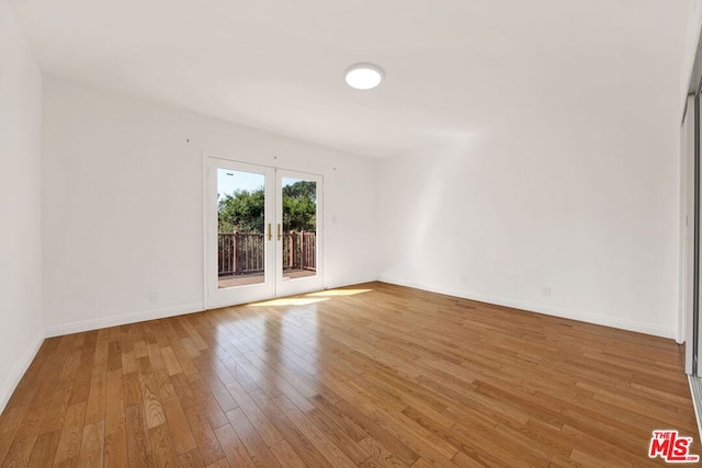 spare room featuring hardwood / wood-style floors and french doors