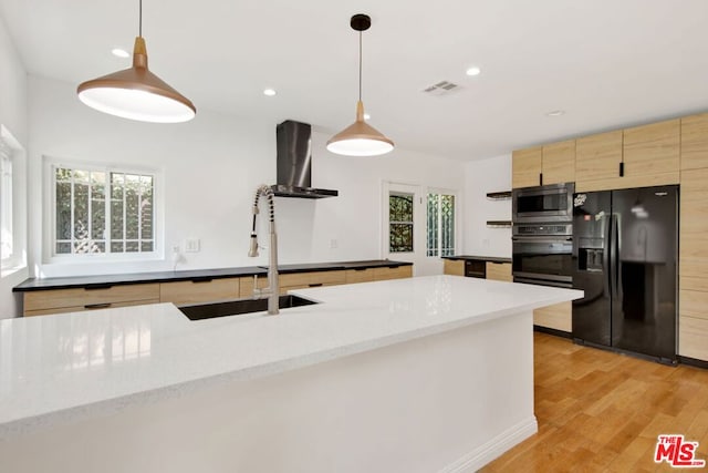 kitchen featuring stainless steel microwave, hanging light fixtures, oven, wall chimney range hood, and black refrigerator with ice dispenser