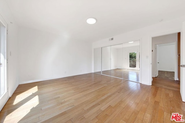 unfurnished bedroom with a closet and light hardwood / wood-style flooring